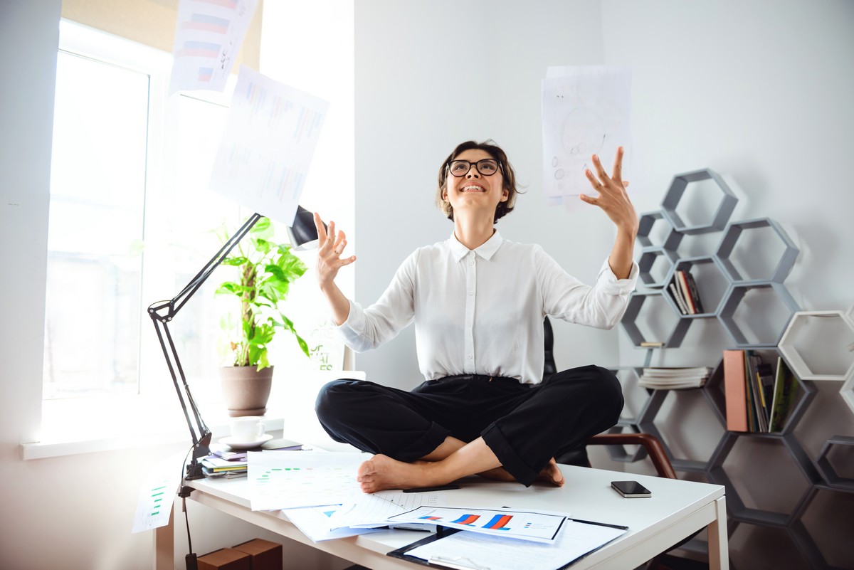 young beautiful businesswoman glasses smiling throwing up papers sitting table workplace office