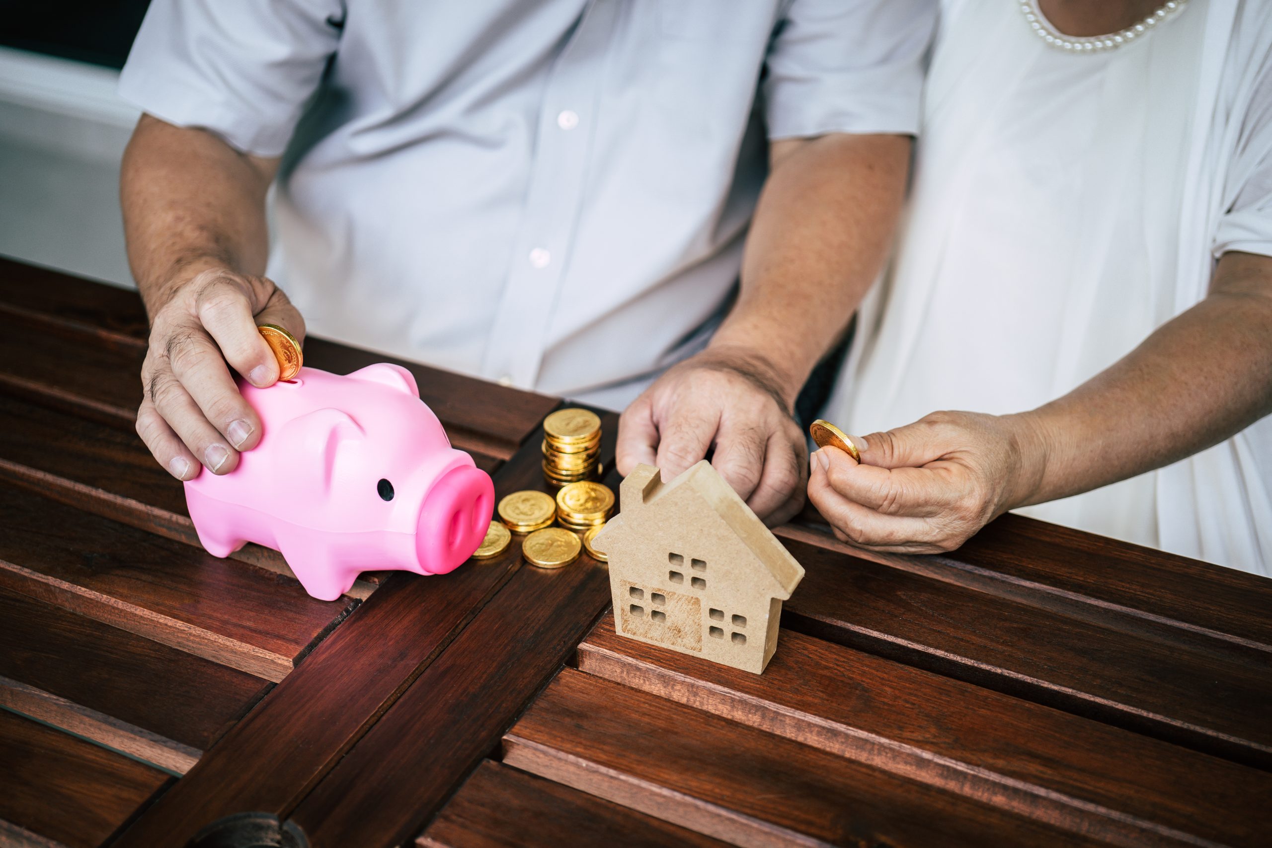 elderly couples talking about finance with piggy bank scaled