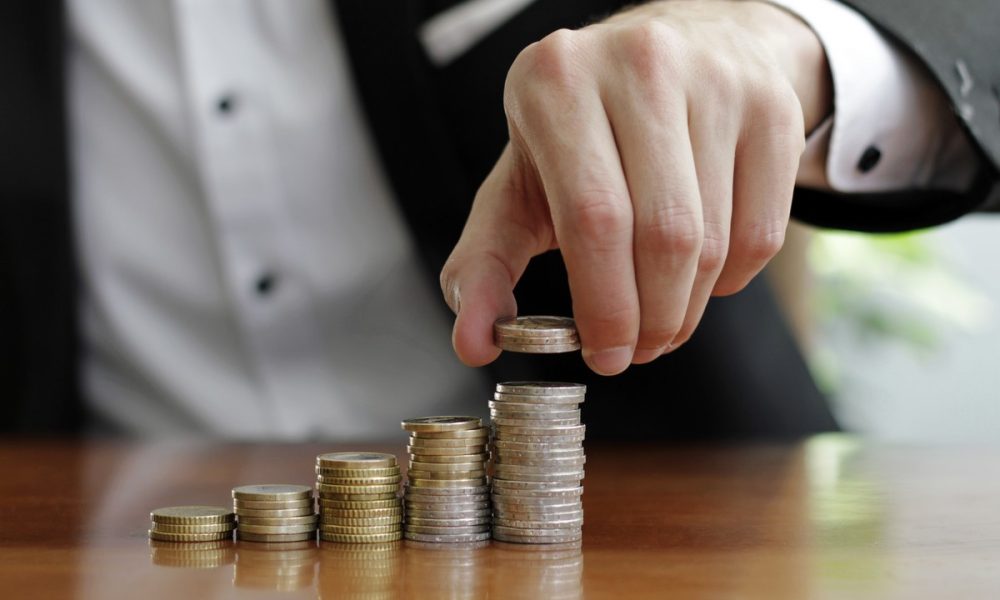 closeup shot businessman s hands counting stacks coins after business success